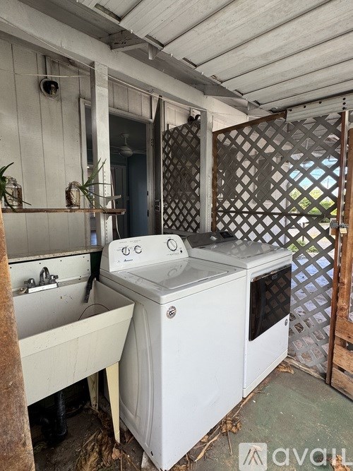 A white washing machine and sink in a cluttered room.