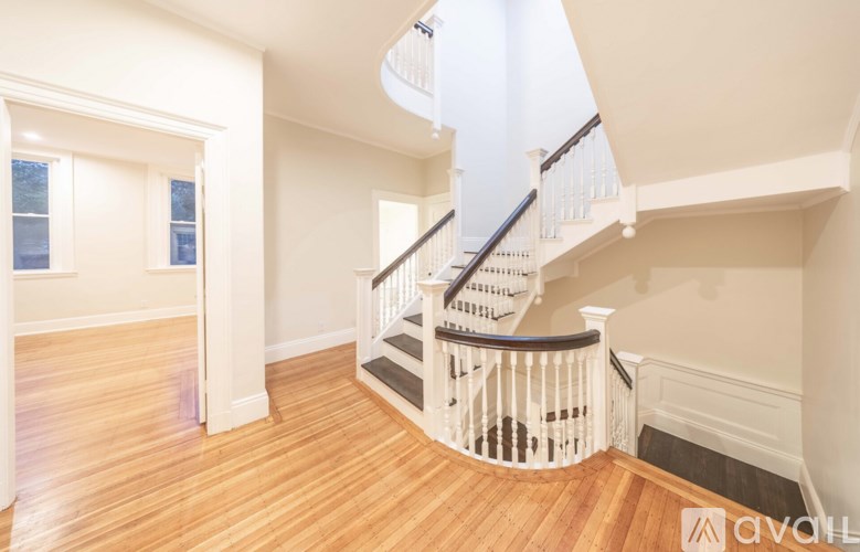 A wooden staircase with a white railing leads up to a second floor.