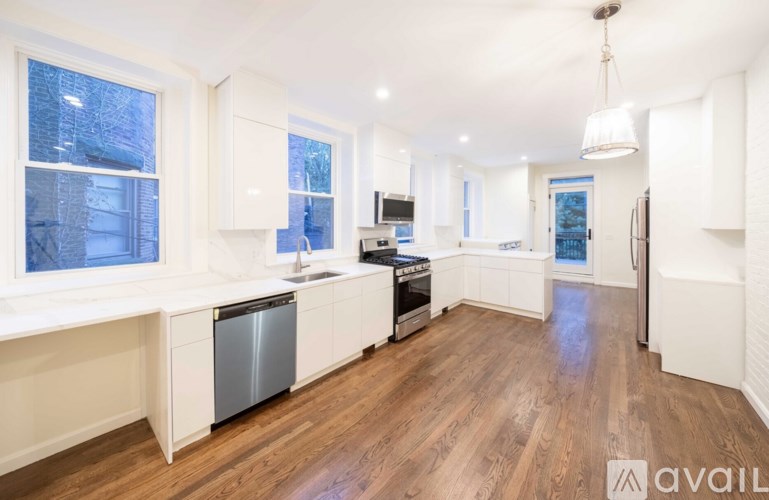 A modern kitchen with white cabinets and a wooden floor.