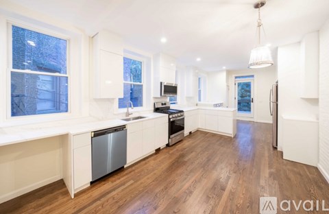 A modern kitchen with white cabinets and a wooden floor.