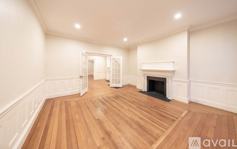 A large empty room with wooden floors and a fireplace.
