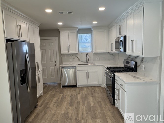 A kitchen with white cabinets and a stainless steel refrigerator.