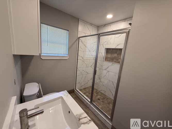 A bathroom with a white sink and a glass shower door.