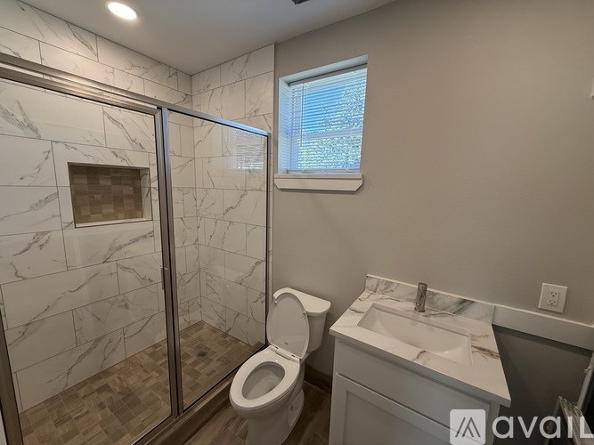 A bathroom with a marble tile shower and a toilet.