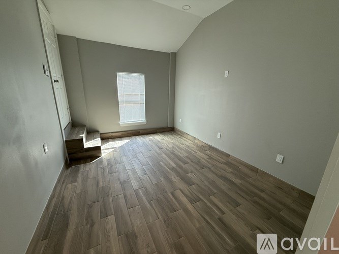 A room with wooden flooring and a window.