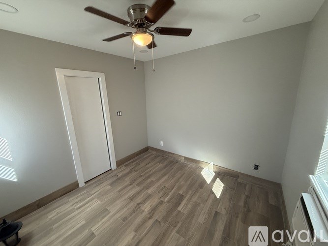 A room with a ceiling fan and wooden flooring.