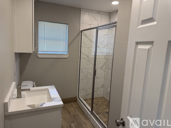 A bathroom with a white sink and a glass shower door.