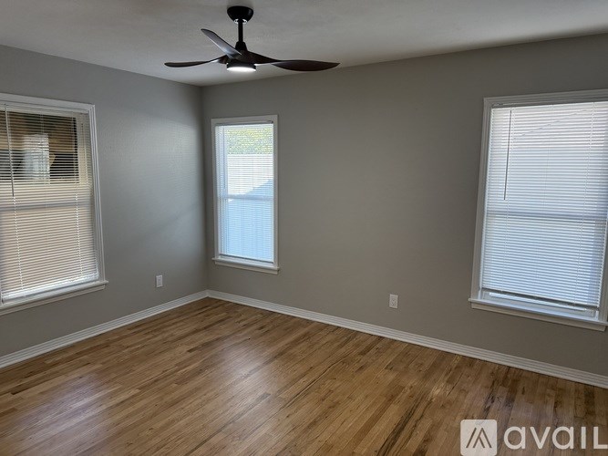A room with a ceiling fan and two windows.