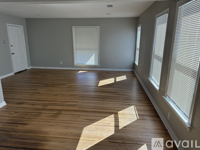 A room with wooden floors and a window with blinds.