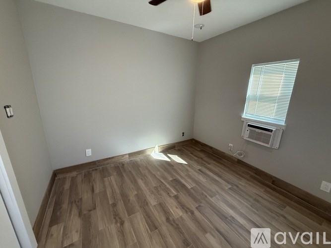 A room with wooden flooring and a window with blinds.