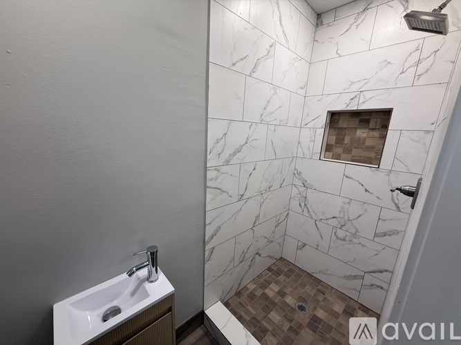 A bathroom with a marble tile shower and a white sink.