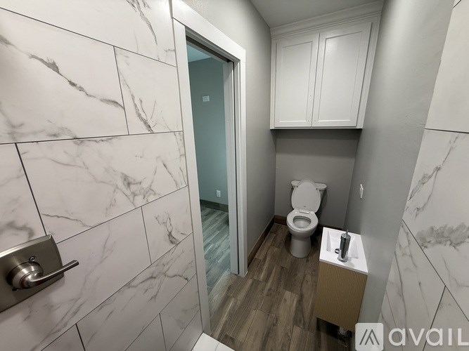 A bathroom with a marble tile wall and a toilet.