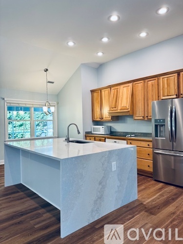 A kitchen with wooden cabinets and a marble island.