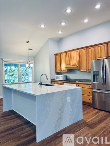 A kitchen with wooden cabinets and a marble island.