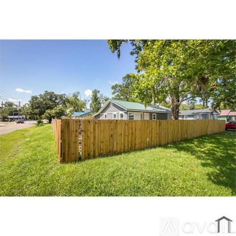 A wooden fence in front of a house with a green roof.