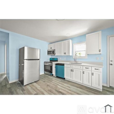 A kitchen with white cabinets and a blue wall.