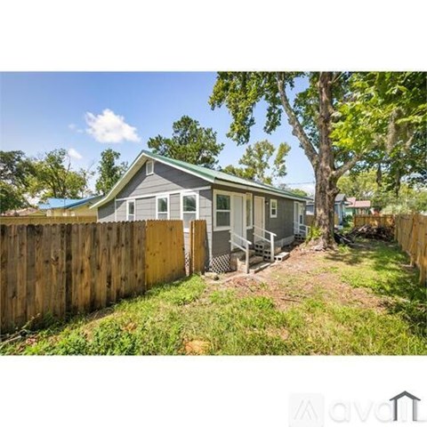 A house with a grey roof and a wooden fence in front of it.