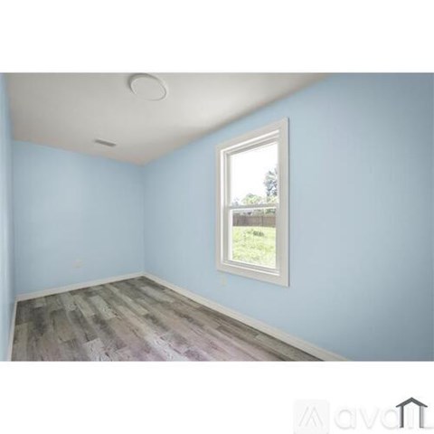 A room with a window and wooden flooring.