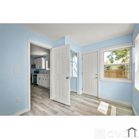 A kitchen with blue walls and white cabinets is visible through an open door.