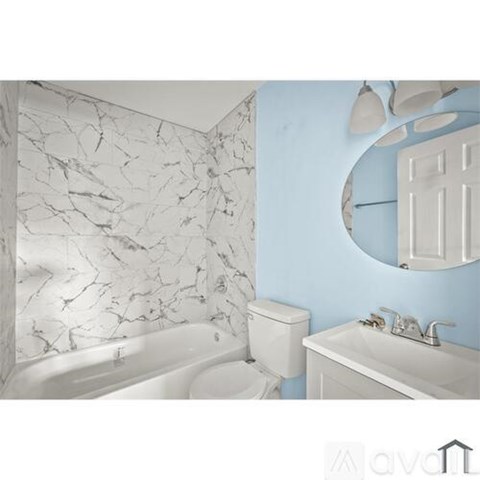 A bathroom with a marble patterned wall and a round mirror.