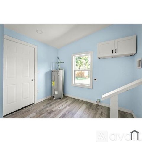 A room with a white door, a window, and a white cabinet on the wall.