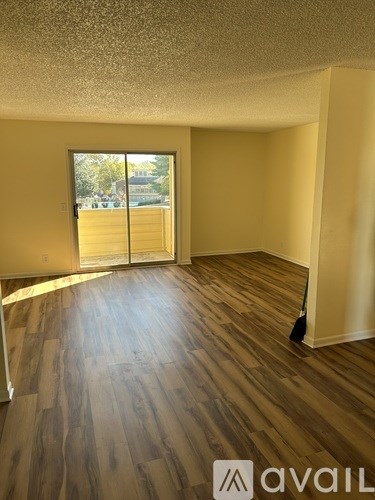 A room with wooden flooring and a window with a view of a parking lot.