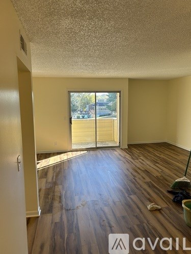 A room with wooden floors and a window overlooking a street.