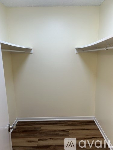 A room with a white door and two white shelves on the wall.
