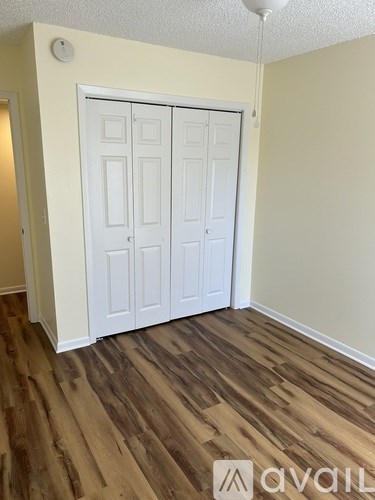 A room with a white door and wooden flooring.