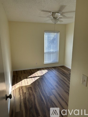 A room with a ceiling fan and a window with blinds.
