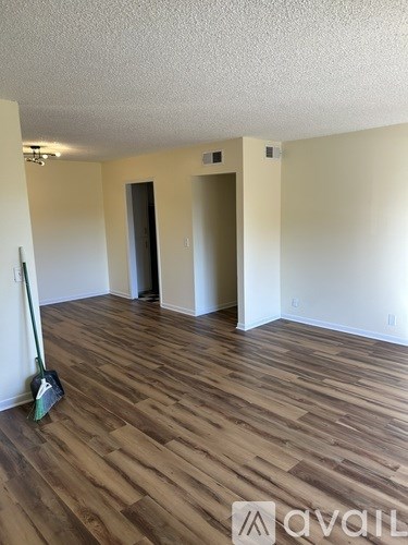 A room with wooden flooring and a broom in it.