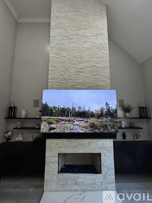 A modern living room with a fireplace and a large screen displaying a forest scene.