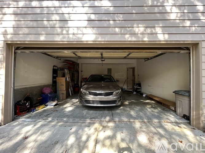 A silver car is parked in a garage with a white wall and a white ceiling.