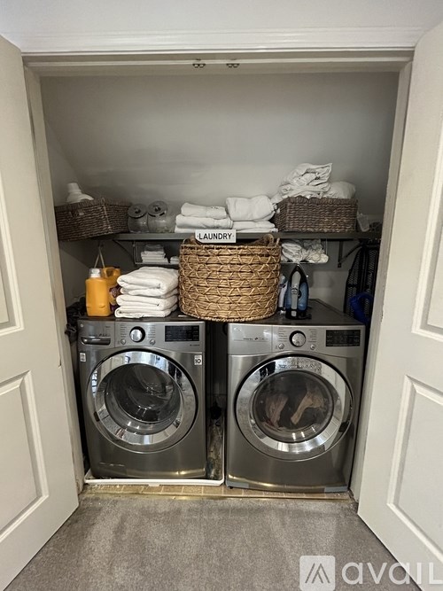 A laundry room with two washing machines and a basket of towels.