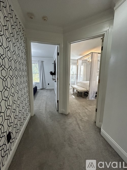A hallway with a carpeted floor and a wallpapered wall.