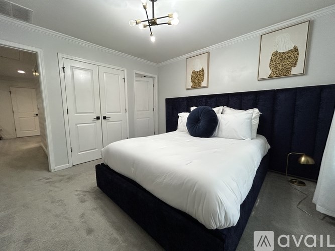 A bedroom with a large bed and two pictures on the wall.