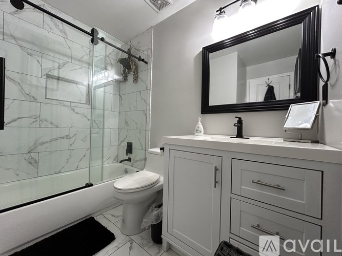 A bathroom with a marble tiled shower and a white toilet.