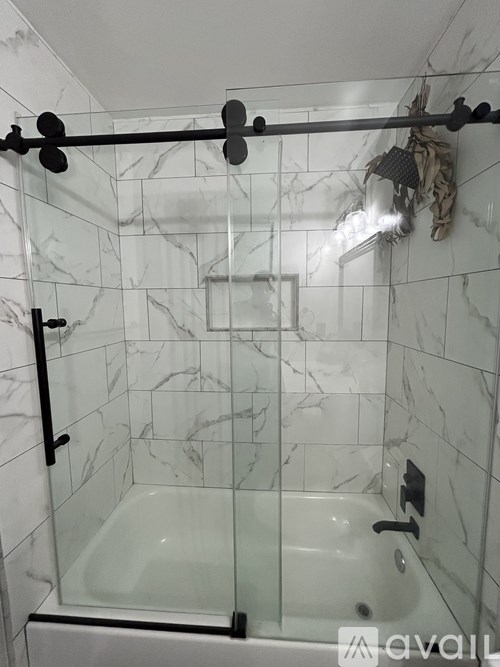 A bathroom with a marble tile wall and a glass shower door.