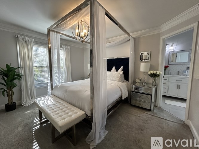 A bedroom with a four poster bed and a bench in front of it.