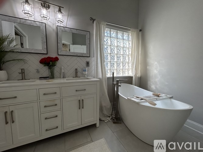 A white bathroom with a tub, sink, and mirror.