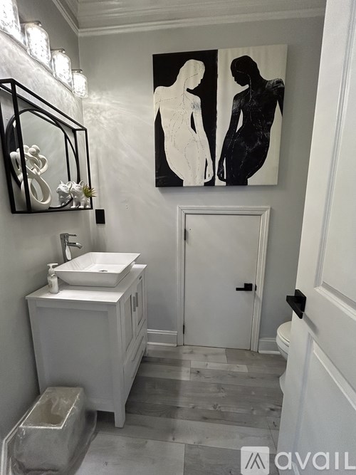 A bathroom with a white sink and a painting of two women.
