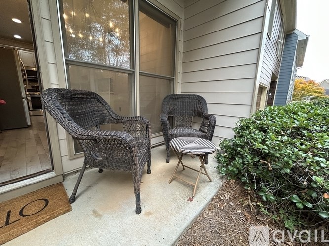 Two chairs and a table are on a porch.