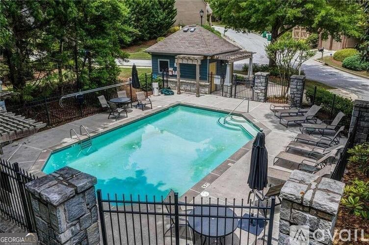A pool surrounded by a black fence and a gazebo in the background.