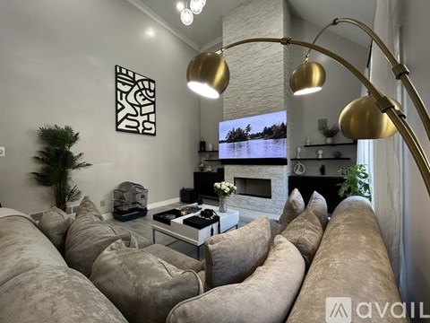 A living room with a grey couch and a TV on a white stand.