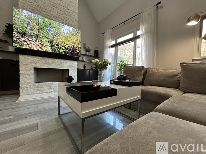 A modern living room with a fireplace and a large TV mounted above it.