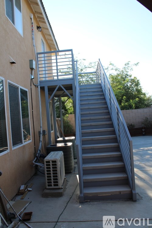 A staircase with a metal railing leads up to a balcony.