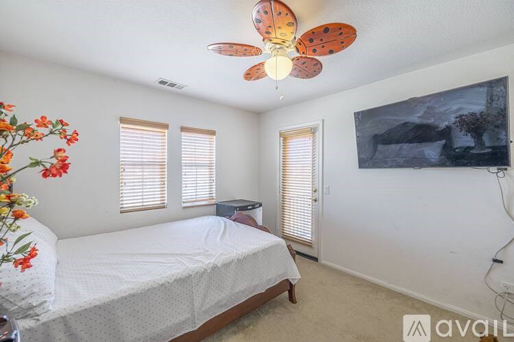 A bedroom with a bed, a ceiling fan, and a painting on the wall.