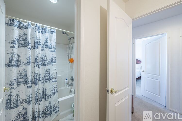 A bathroom with a shower curtain featuring a ship pattern.