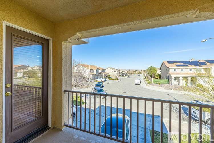 A balcony with a view of a street with cars and houses.