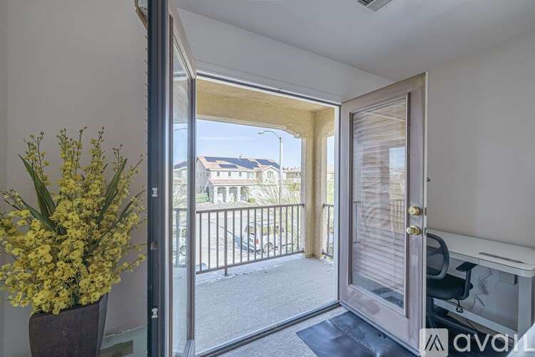 A balcony with a glass door and a vase of yellow flowers on the floor.